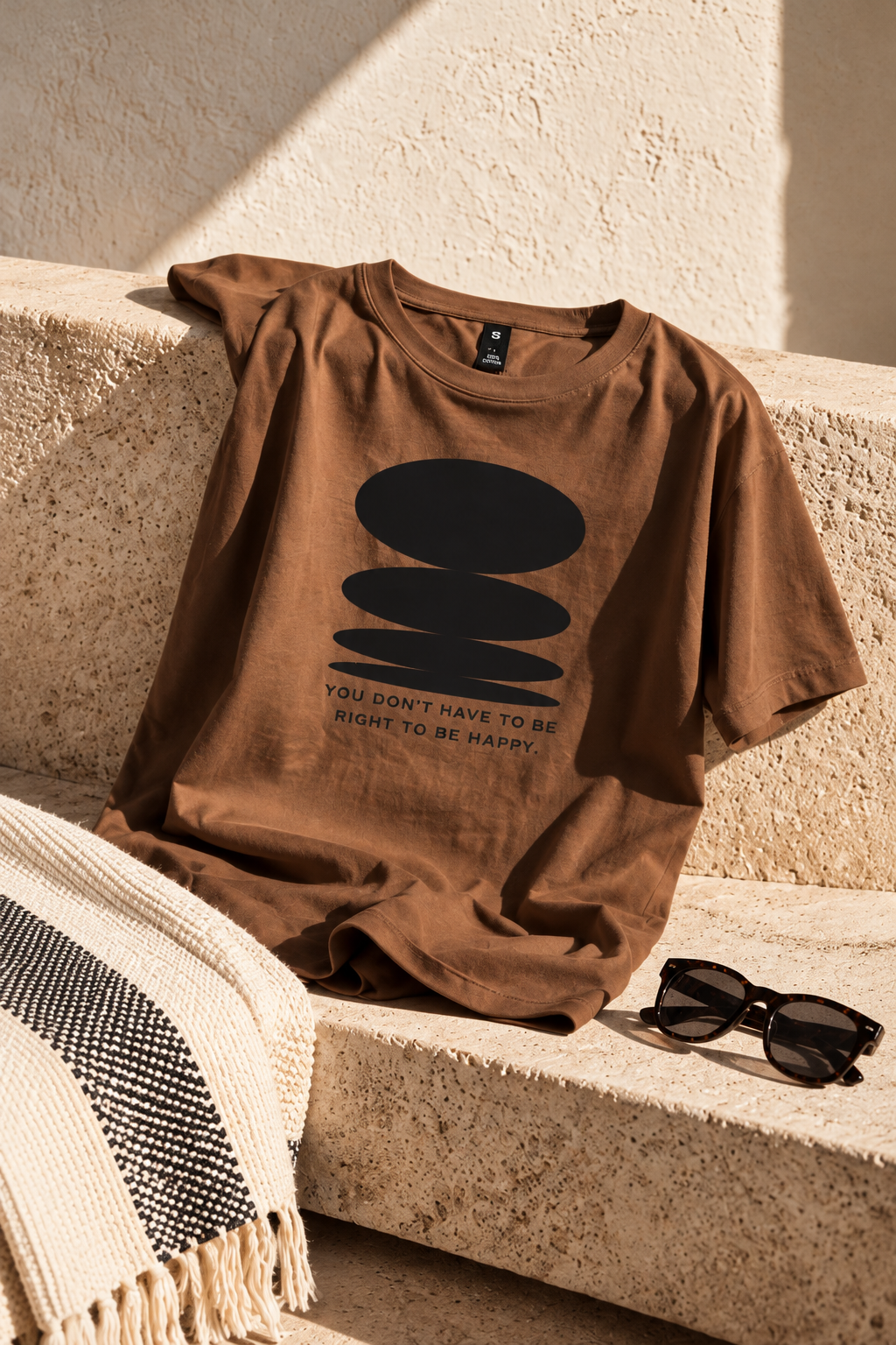 You Don’t Have to Be Right to Be Happy — brown T shirt on stone bench