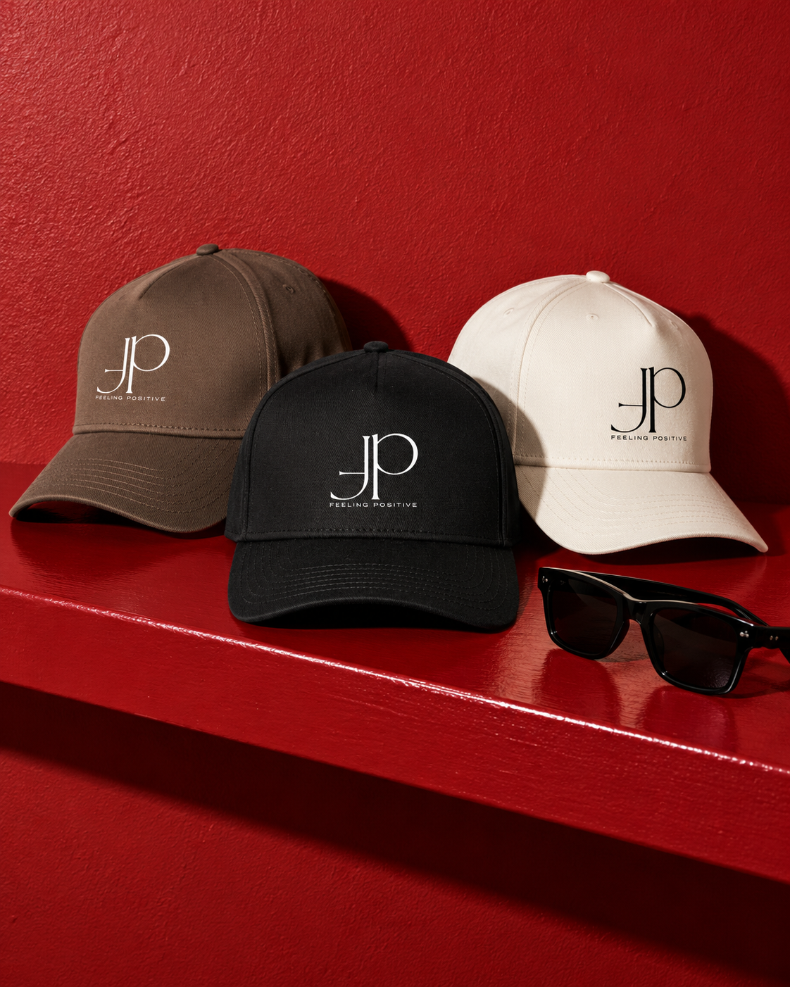 Brown, black and cream caps with the FP monogram and “Feeling Positive” lettering on a red shelf.