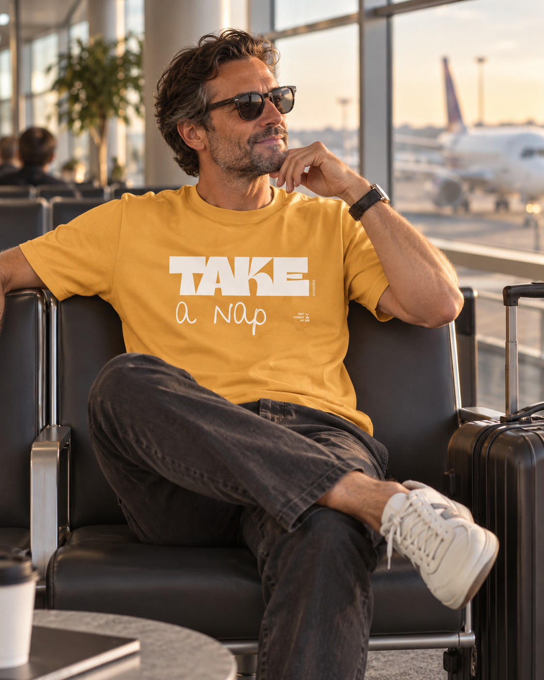 Man in a golden yellow Take a Nap T-shirt relaxing in an airport lounge.